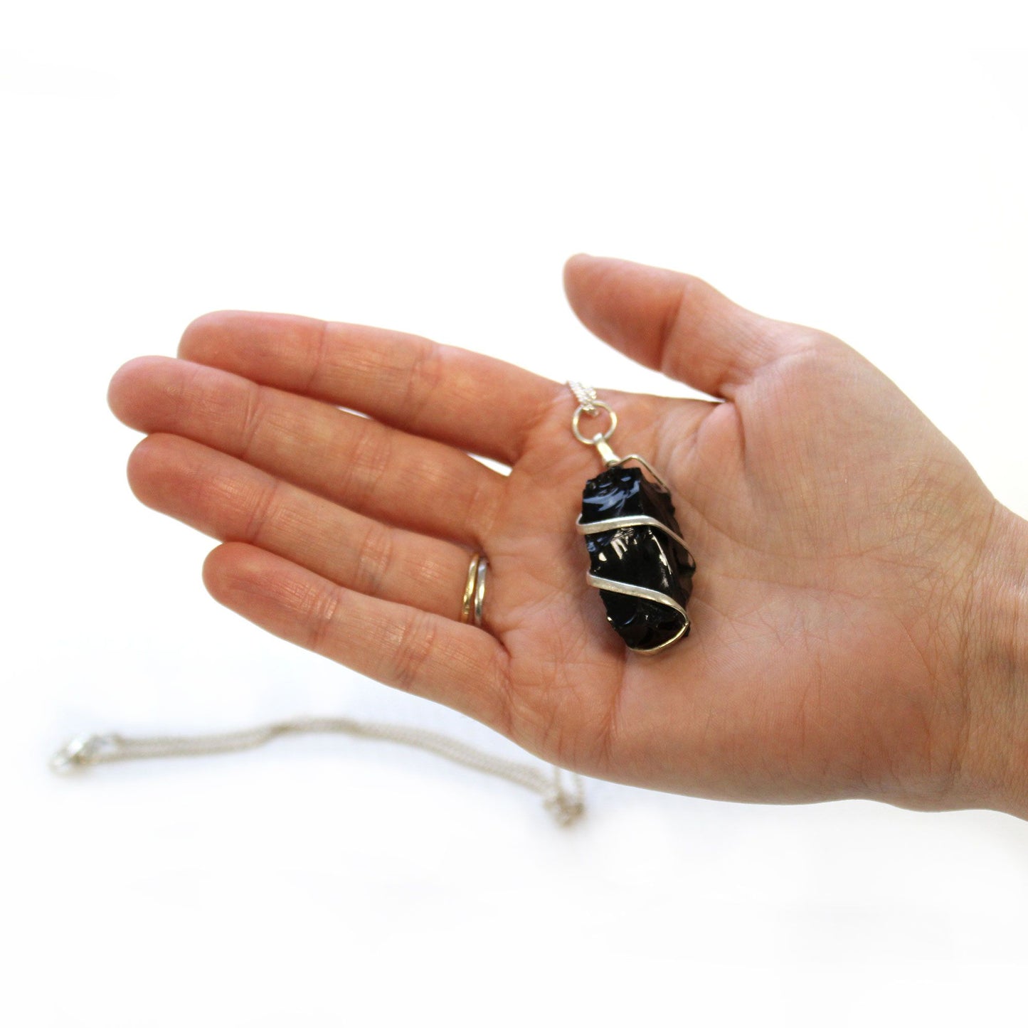Hand holding Cascade Wrapped Gemstone Necklace - Rough Black Onyx on a white background