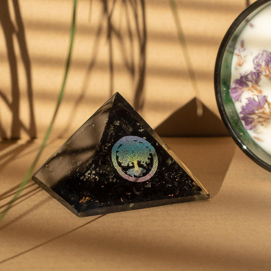 Pyramid-shaped crystal with a tree of life symbol on a beige surface
