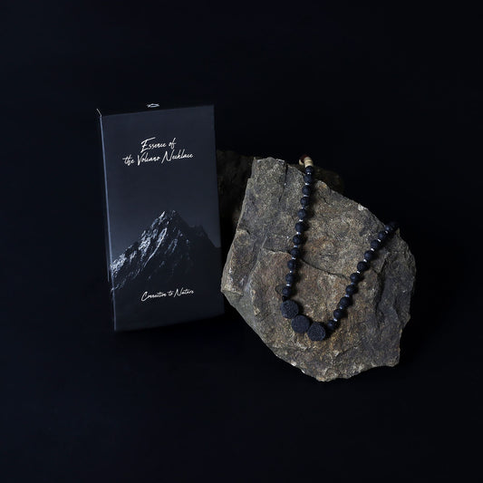 Essence of the Volcano Necklace on a rock with a black box labeled 'Essence of the Numinous' on a dark background