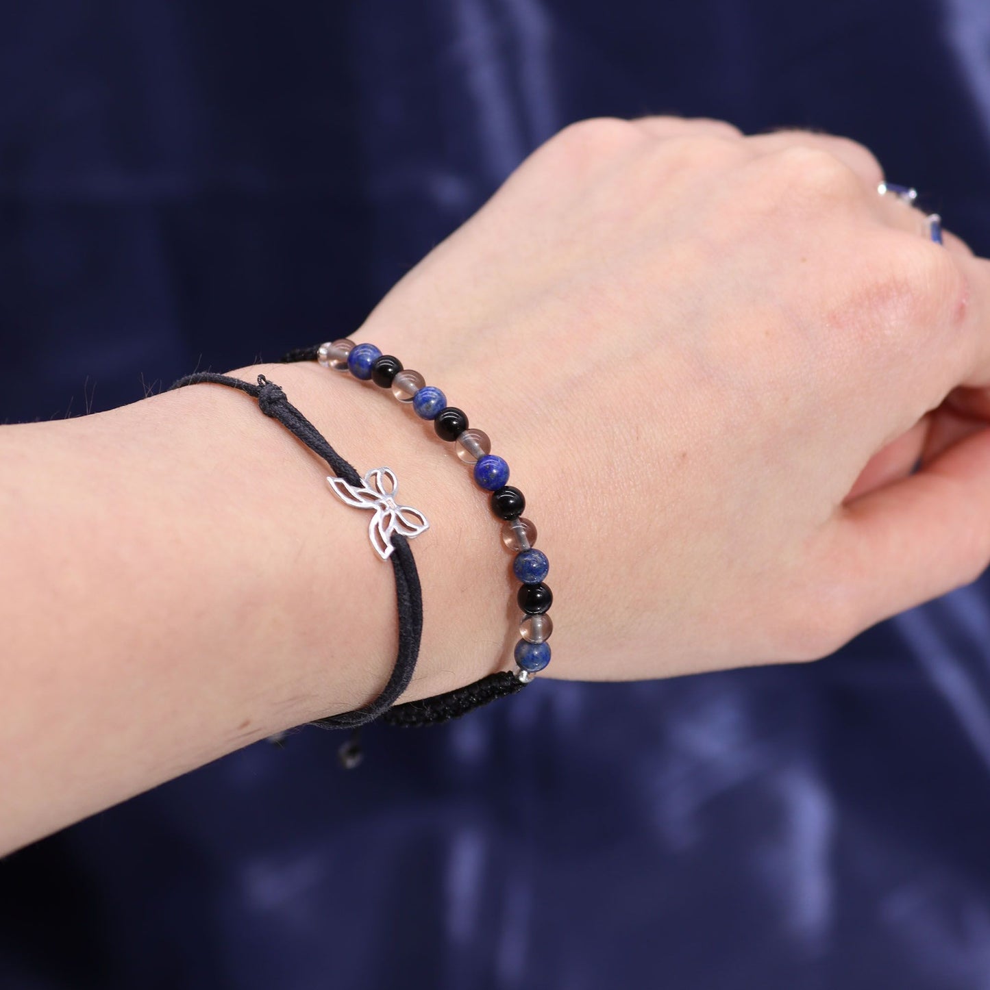 Hand wearing a gemstone bracelet on a dark blue background