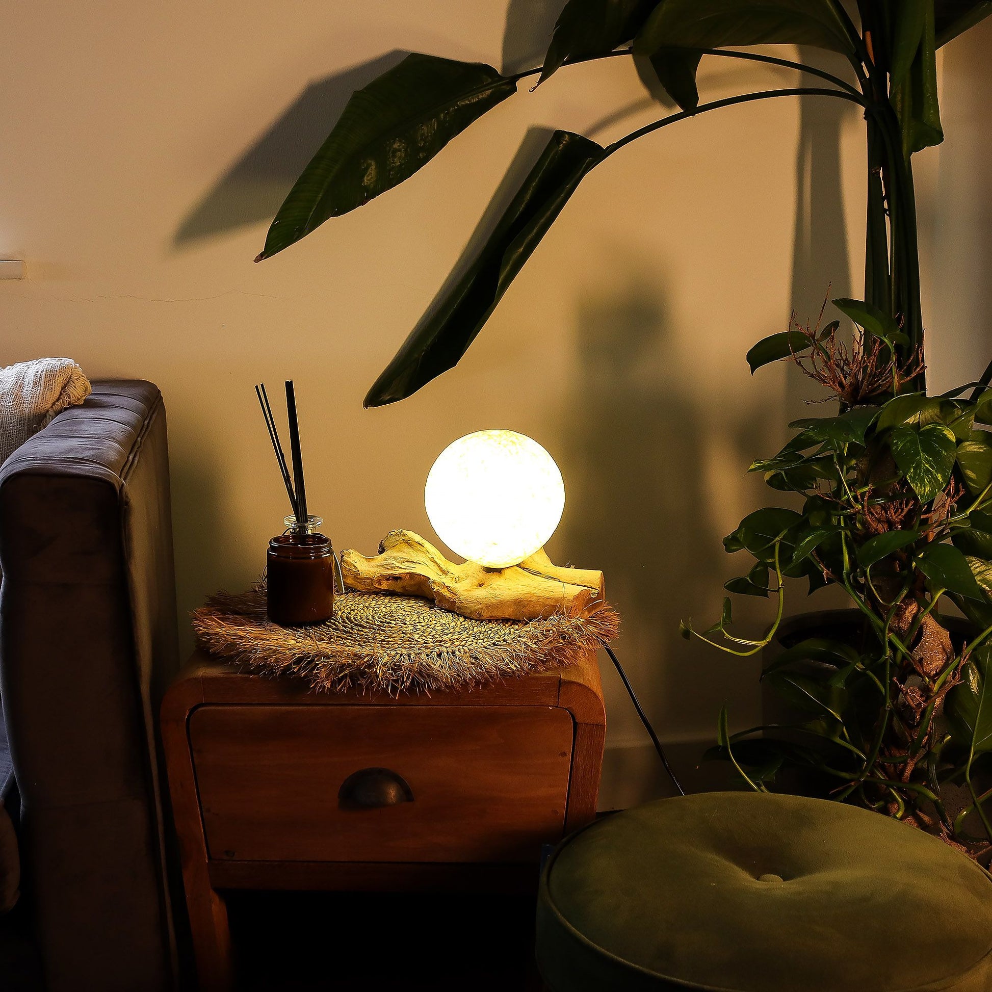 Nestled corner with a wooden side table, glowing lamp, and plants