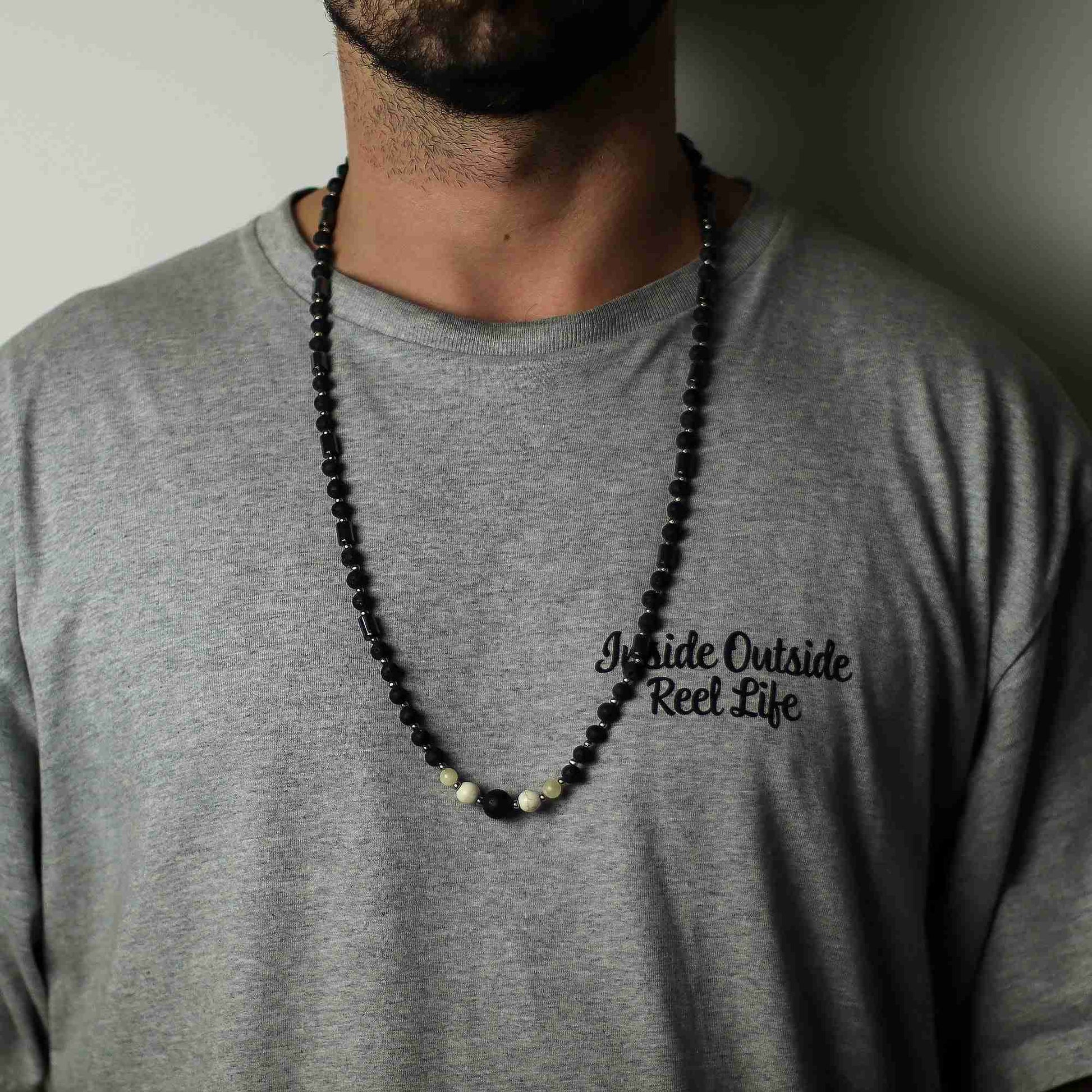 Person wearing a gray t-shirt with an essence of the volcano necklace