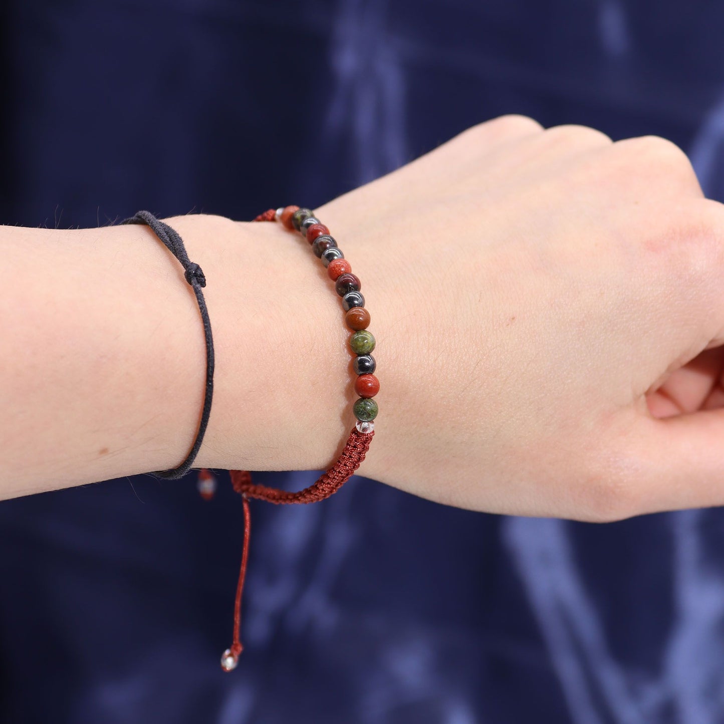 Close-up of a wrist wearing a red beaded bracelet against a dark background