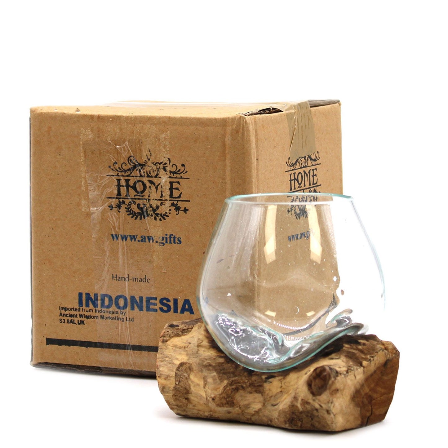 Glass vase on a wooden block with a cardboard box labeled 'HOME' and 'Indonesia' in the background.