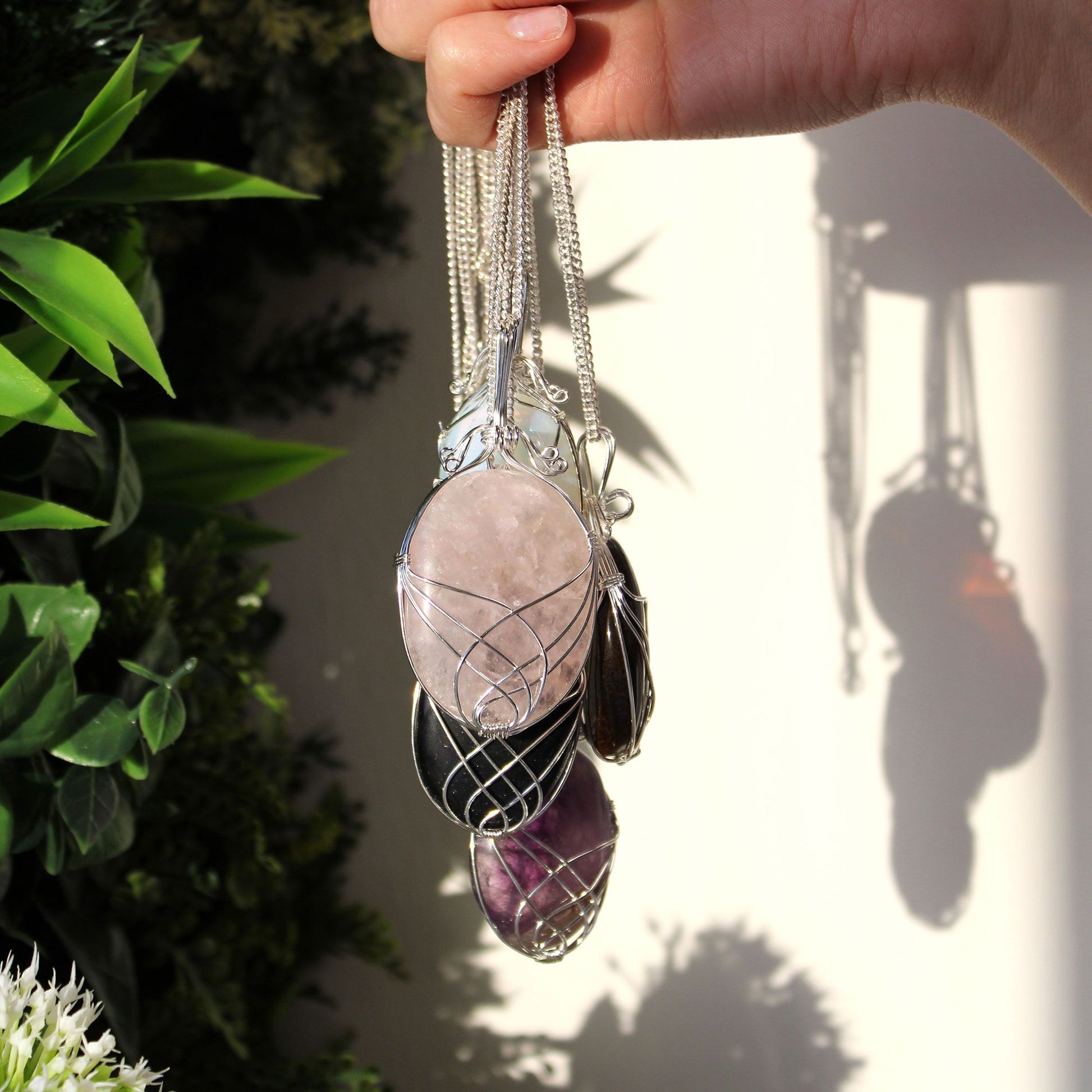 Hand holding a set of crystal pendants with a blurred natural background
