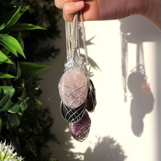 Hand holding a set of crystal pendants with a blurred natural background
