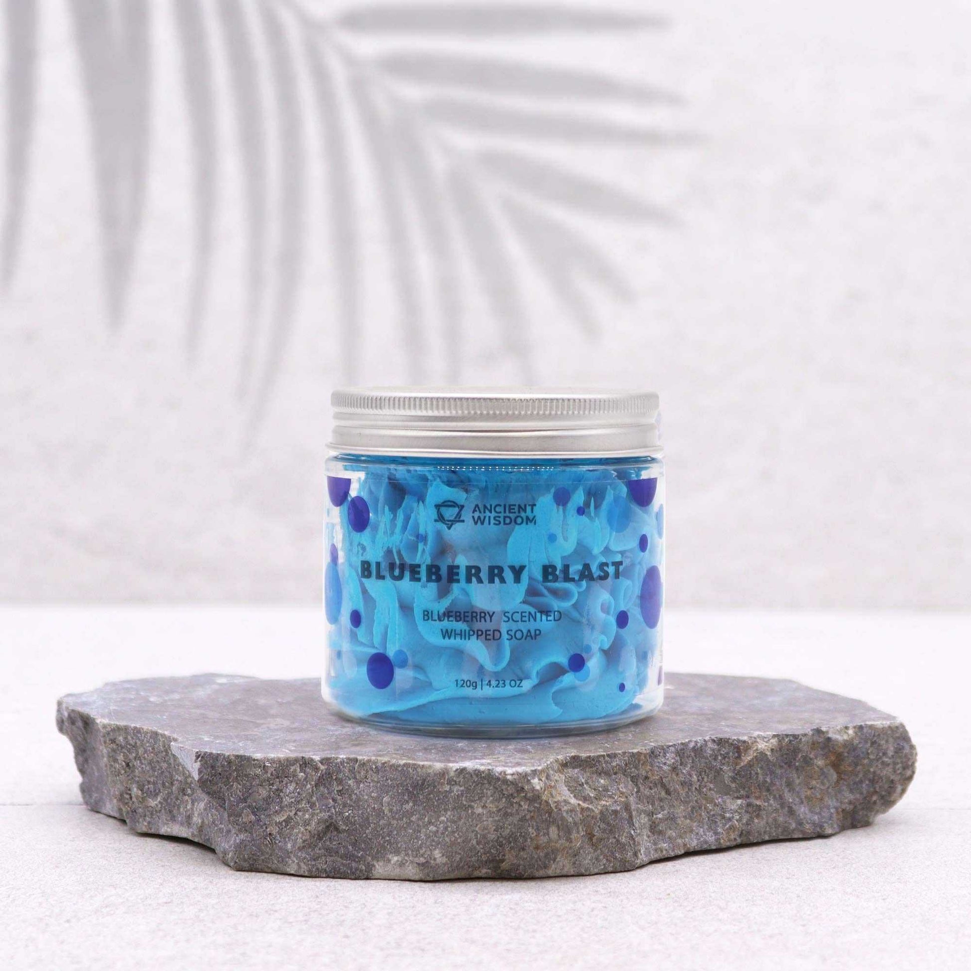 Jar of blueberry blast whipped soap on a stone surface with a white background