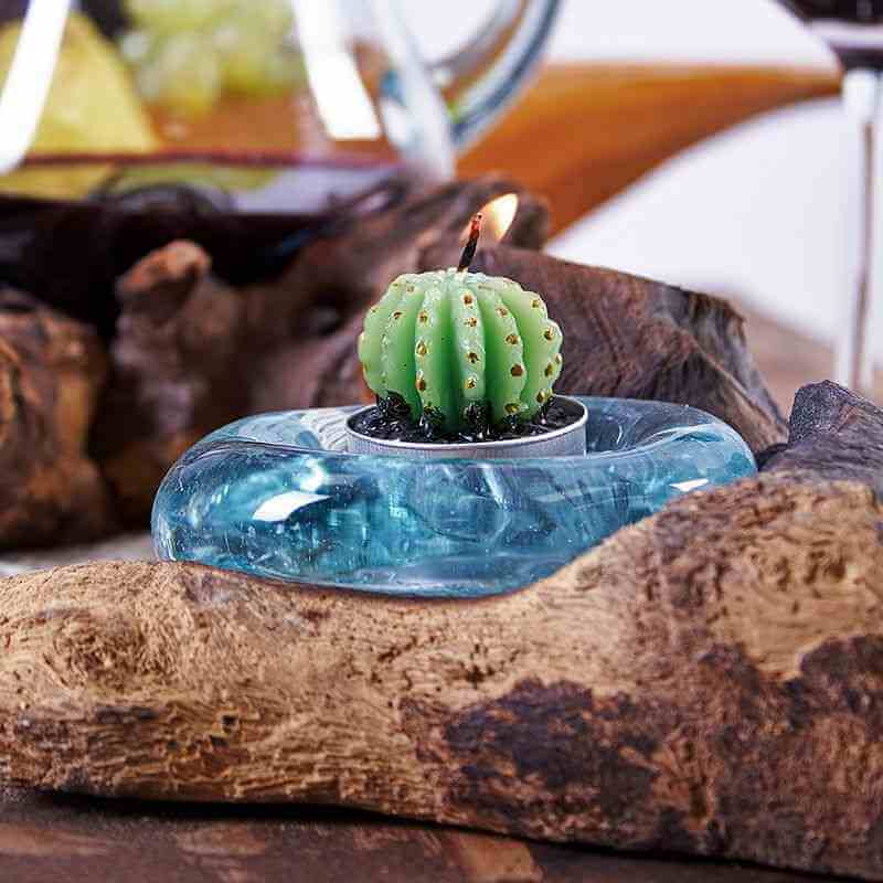 Candle shaped like a cactus in a blue holder on a wooden surface