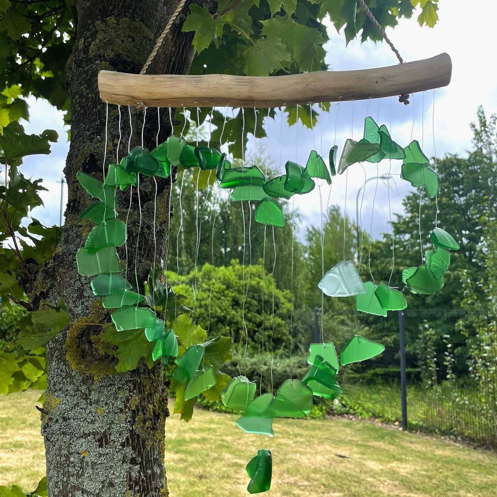 Recycled Glass Wind Chime - Green hanging from a tree in a garden setting