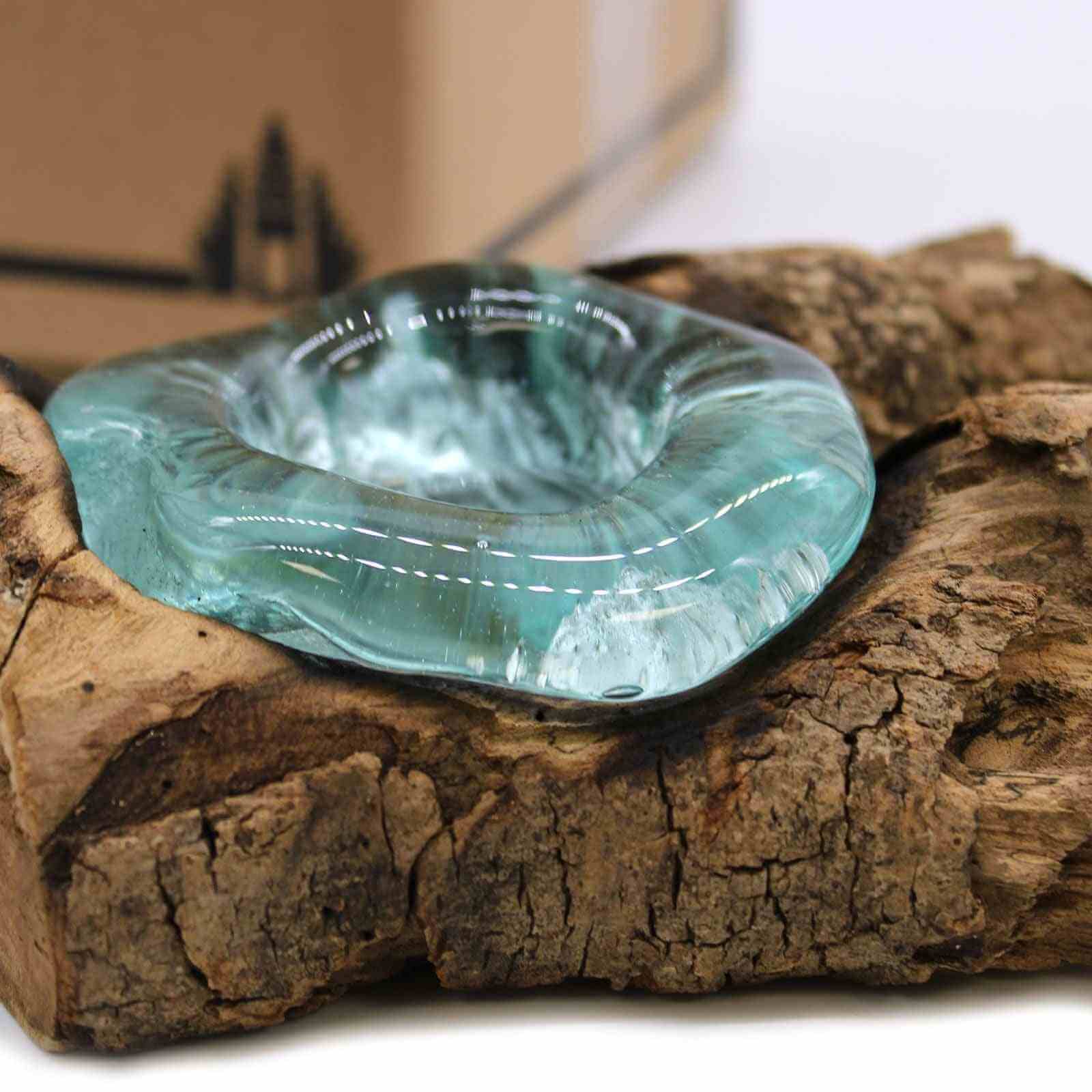 Turquoise molten glass bowl on a wooden log