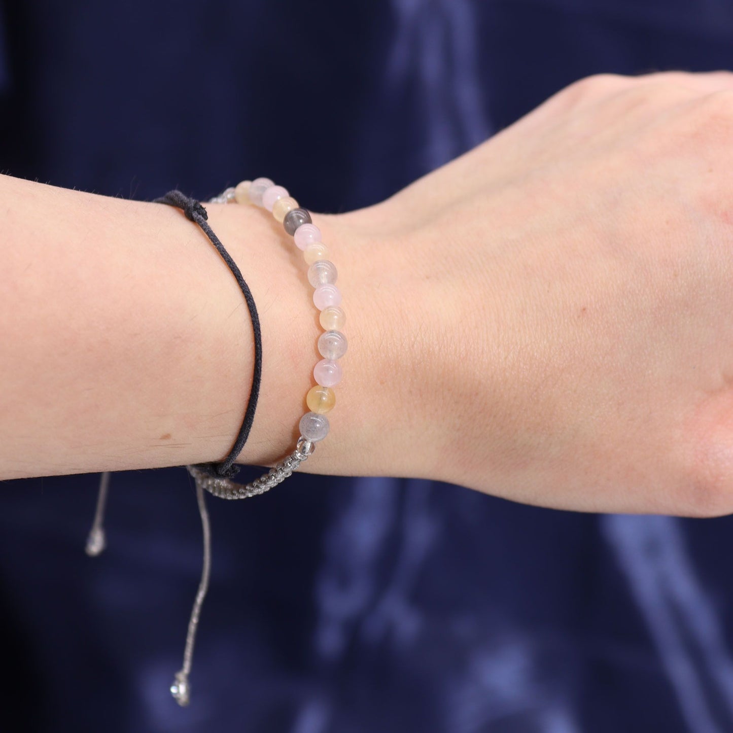 Close-up of a wrist wearing a gemstone bracelet against a dark background