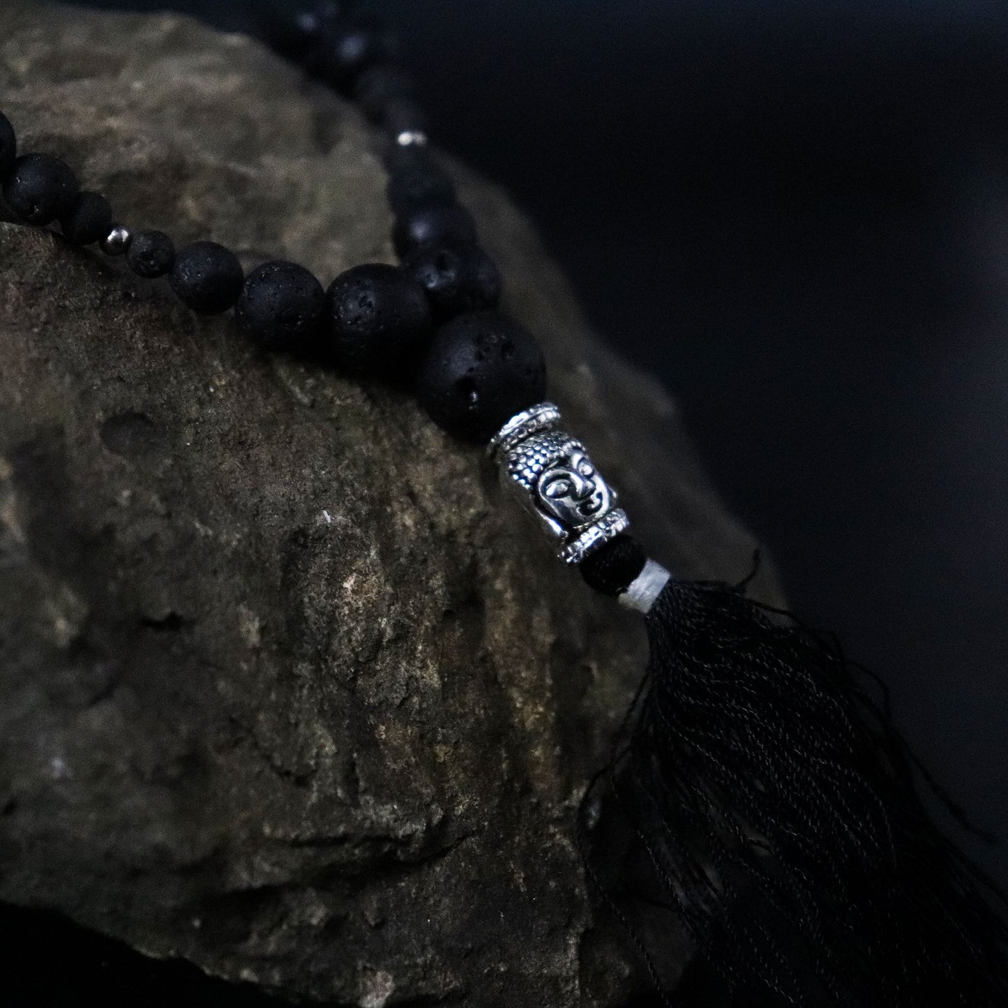 Black beaded necklace with a silver tassel on a dark background