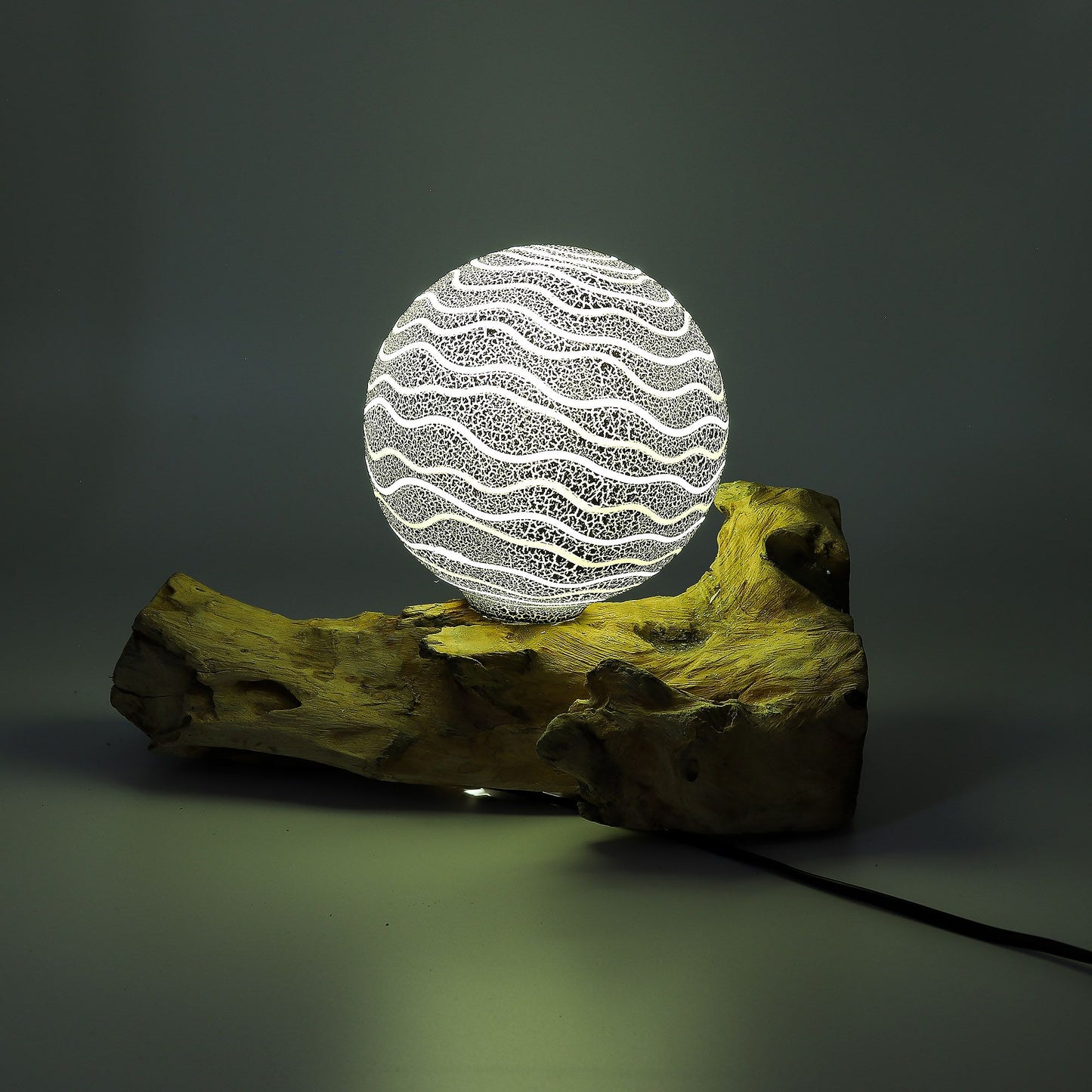 Decorative lamp with wavy pattern on a wooden base against a dark background