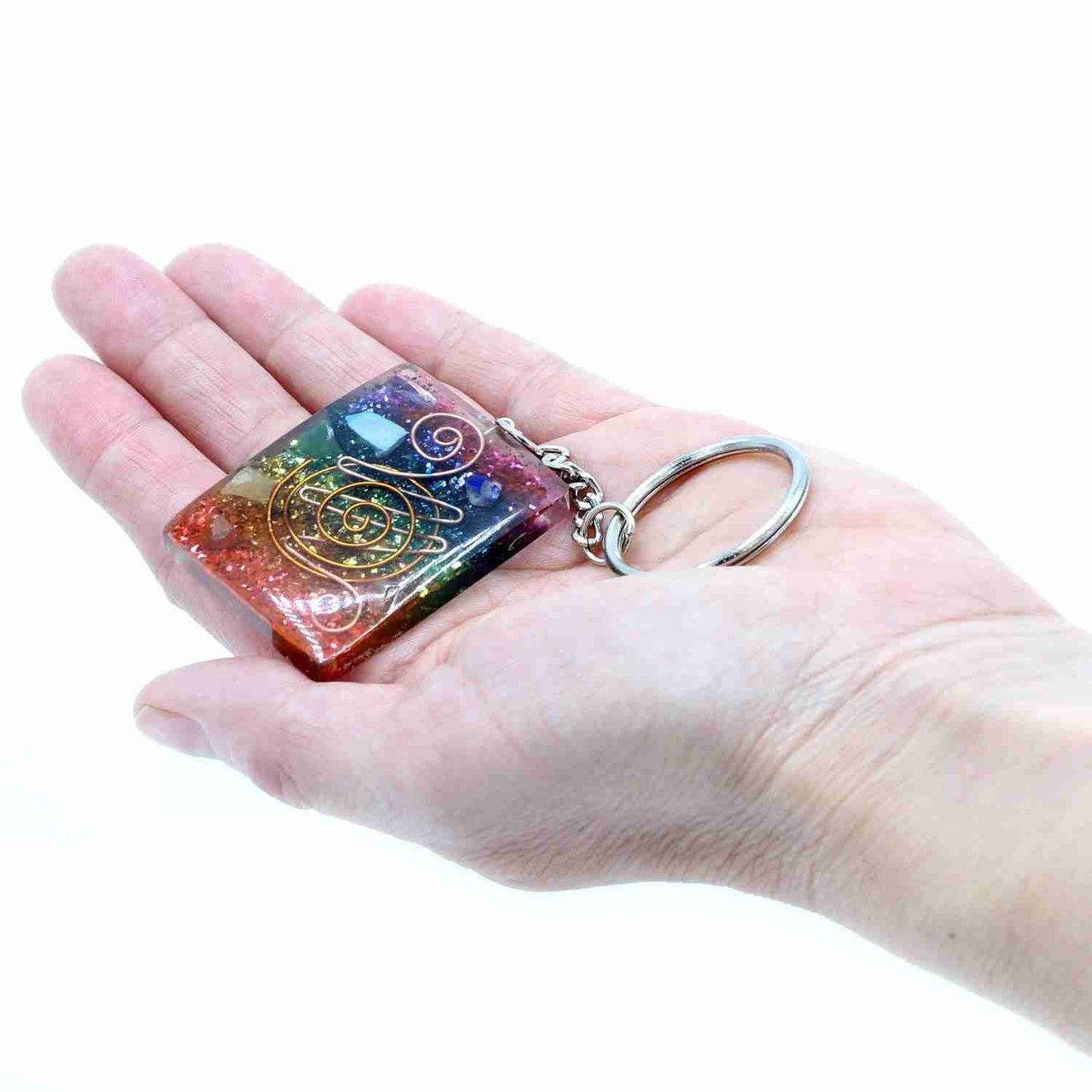 Hand holding a Orgonite Power Keyring - Home Protect Copper and Chakra on a white background