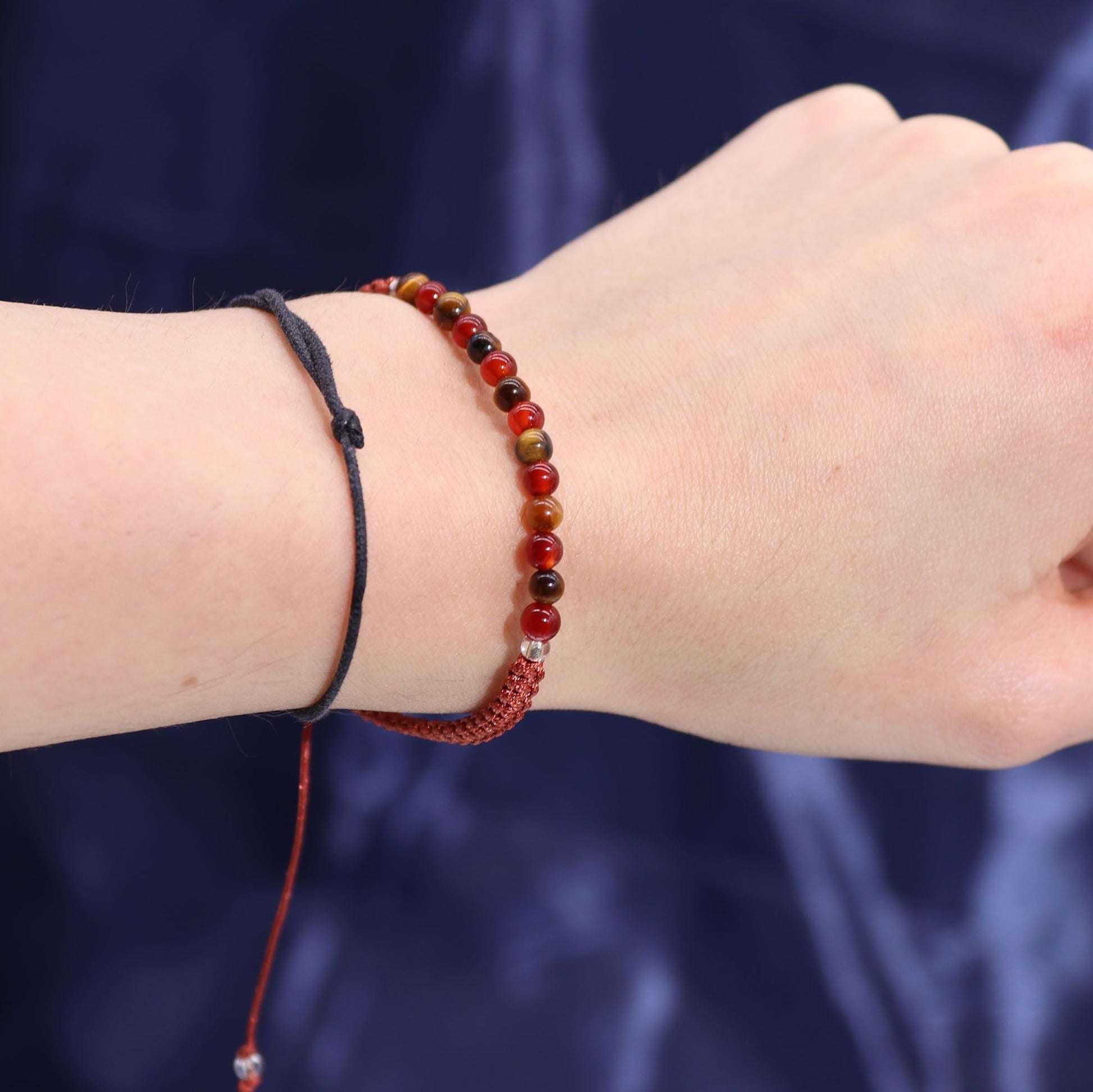 Close-up of a wrist wearing gemstone bracelets against a dark background
