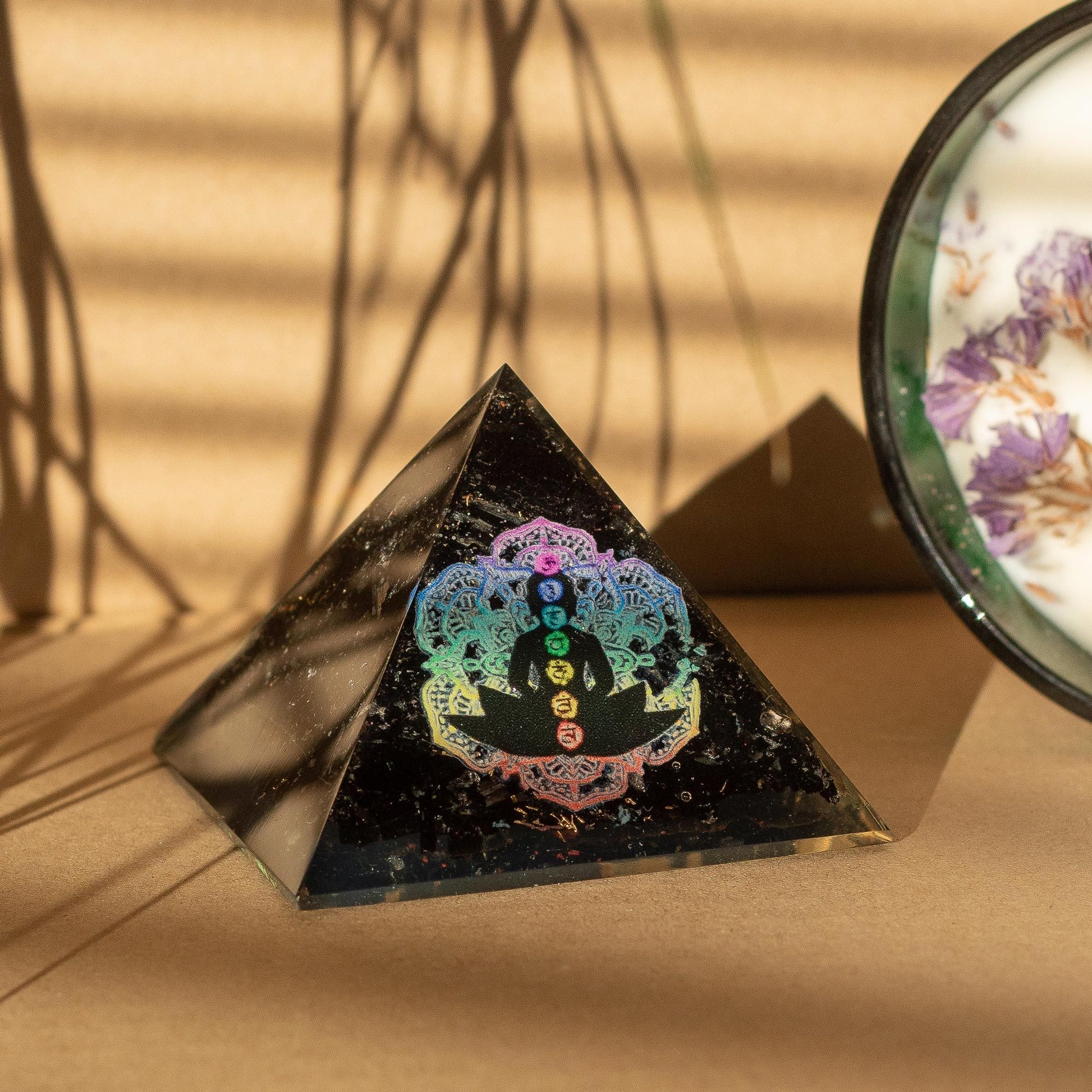 Pyramid-shaped crystal with chakra design on a beige surface