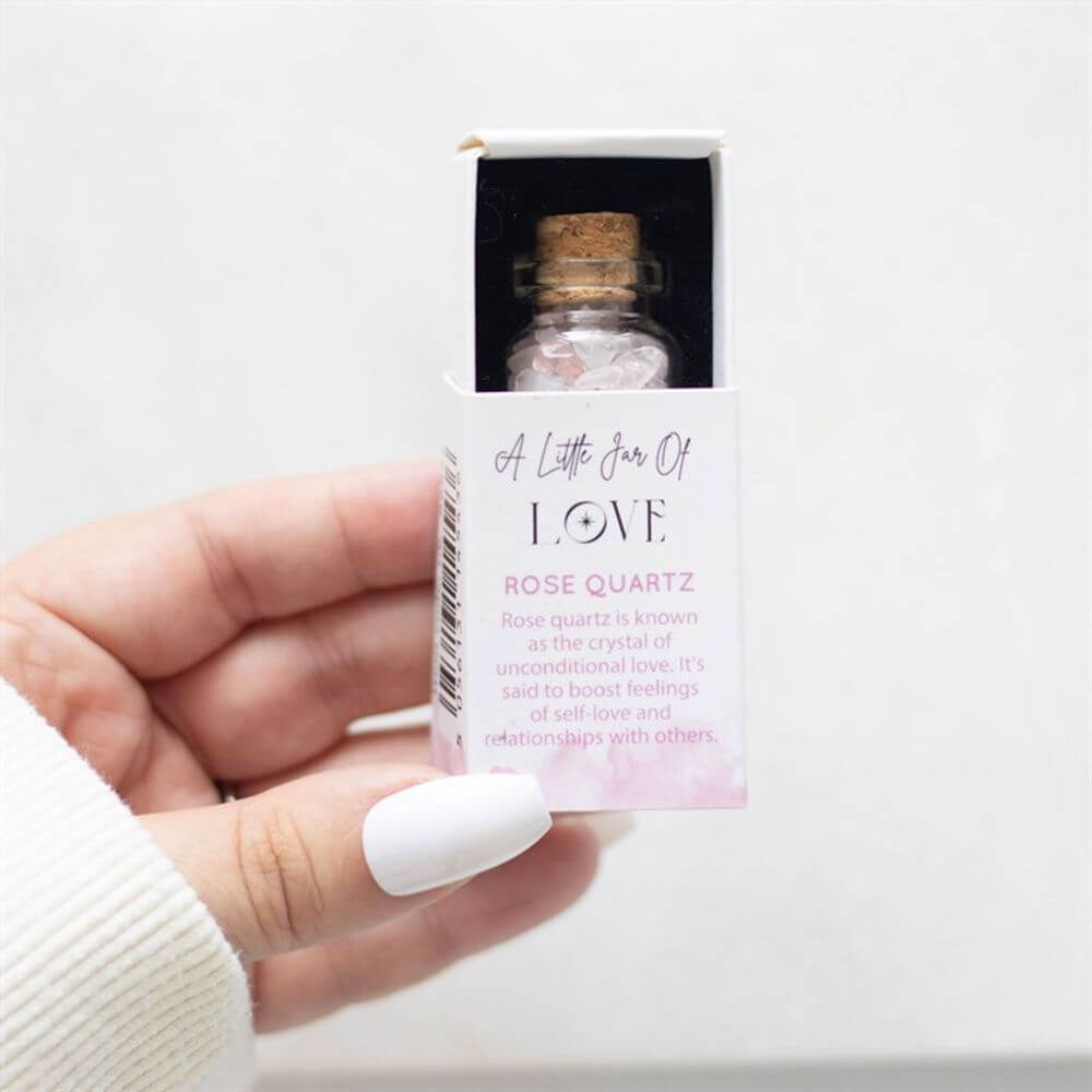 Hand holding a pocket-sized Jar of Love filled with rose quartz crystals, promoting unconditional love and healthy relationships.
