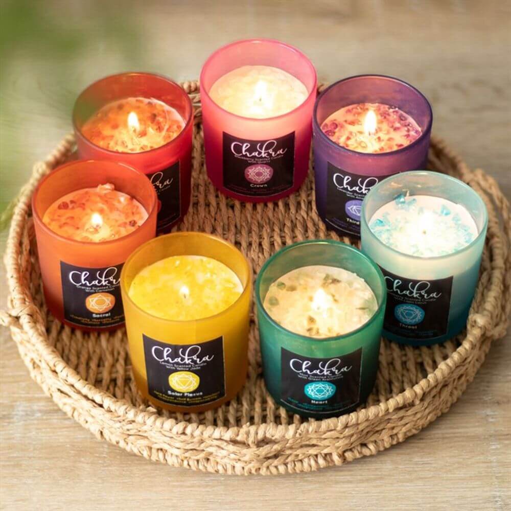 Colorful array of seven scented candles in frosted glass holders on a woven tray, lit and glowing.